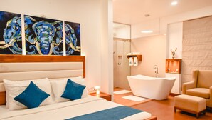 A modern hotel room with a large bed, a bathtub, and a seating area. - Airavata Boutique Resort (Kandy)