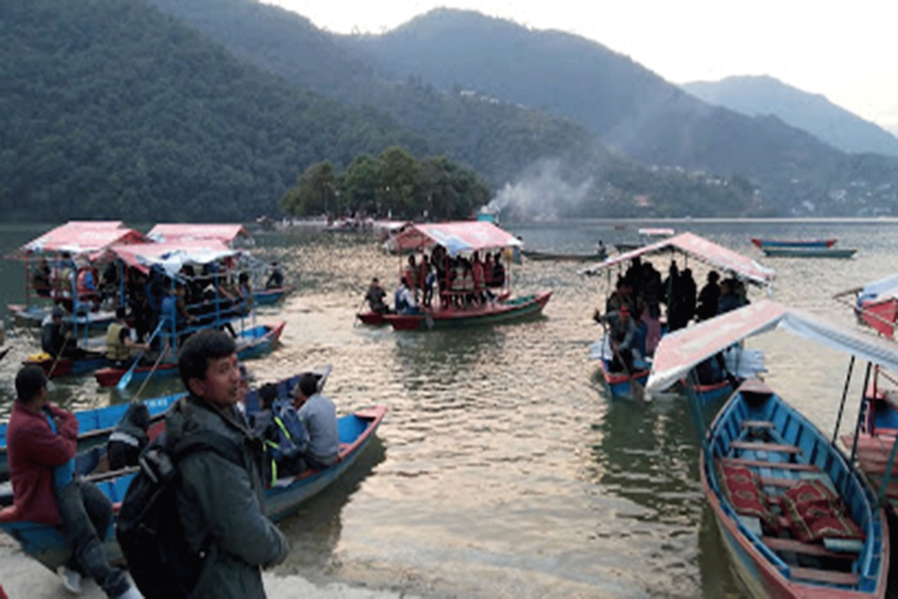 A group of boats on a lake with people on them.