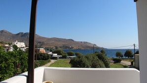 A balcony with a view of a coastal landscape, including hills and a body of water. - Hotel Nefeli (Leros)