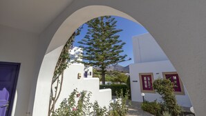 A white building with a purple door and a tree in front. - Hotel Nefeli (Leros)