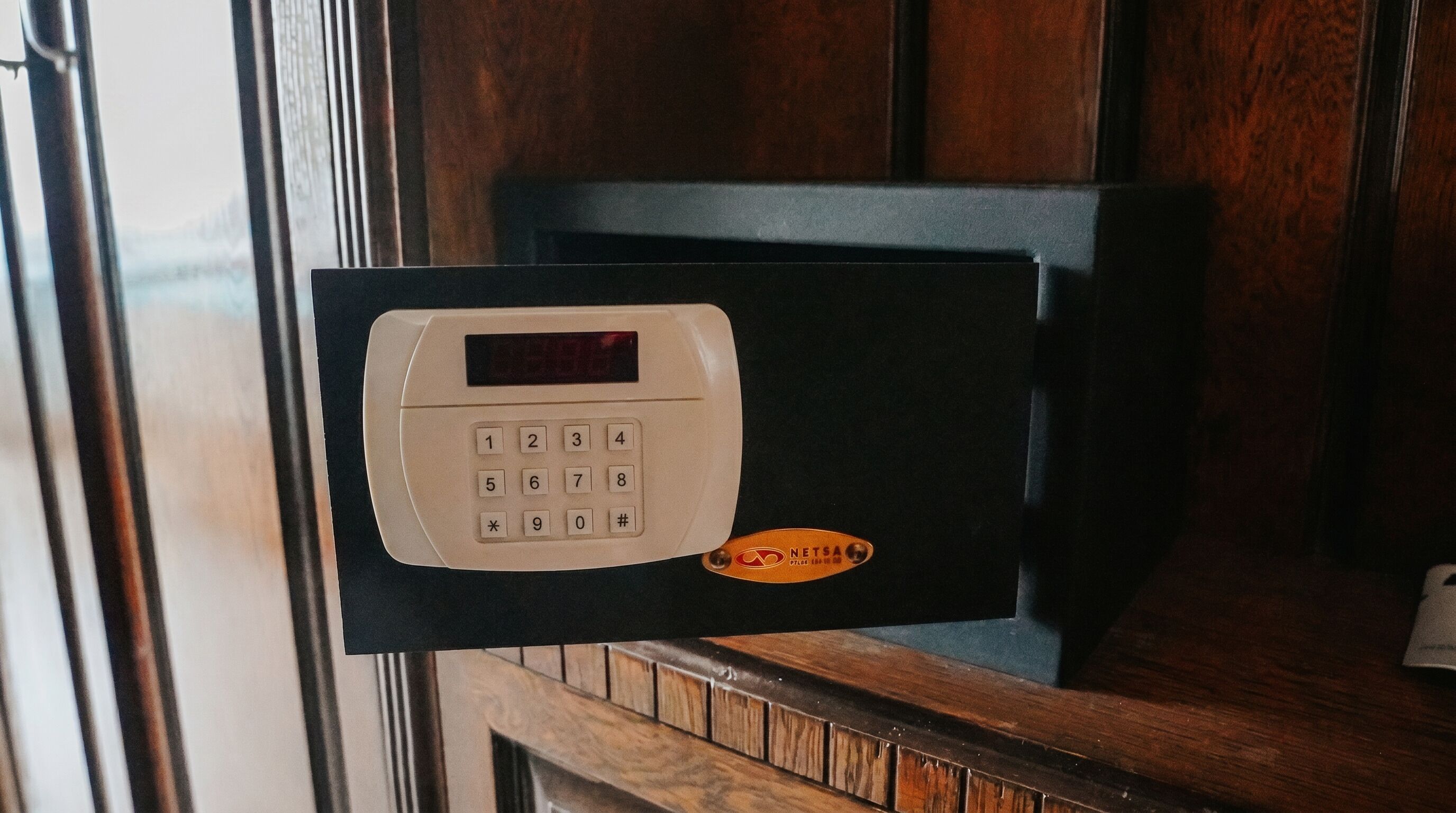 A keypad lock on a door with a wooden frame.
