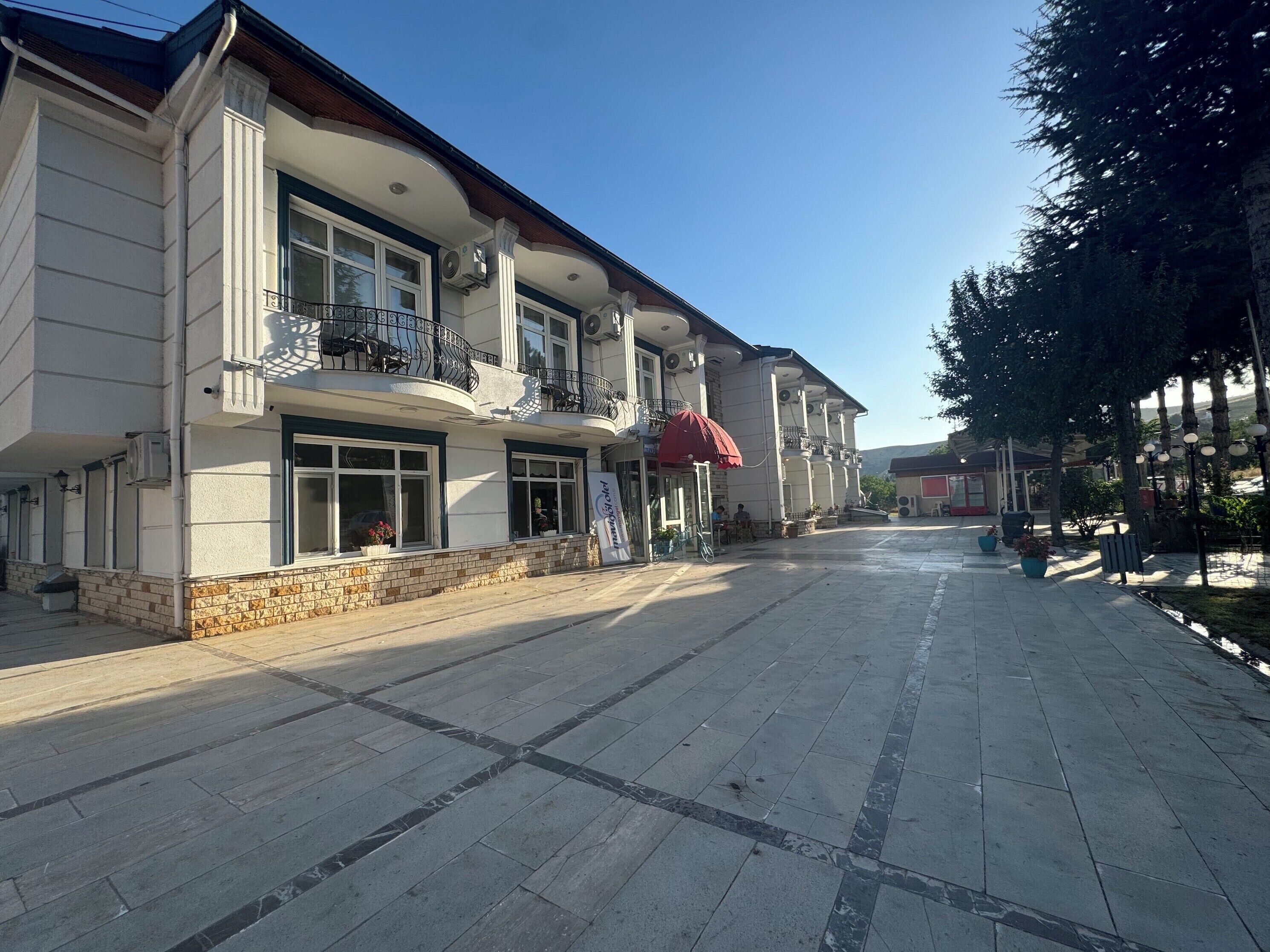A building with a balcony, large windows, and a tiled walkway.