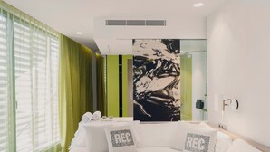 A modern hotel room with a large bed, green curtains, a large abstract painting, and a green accent wall. - Hotel Rec Barcelona - Adults only (Barcelona)