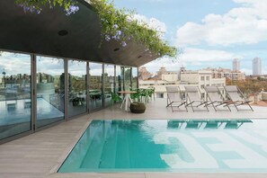 A rooftop pool with clear glass walls, a wooden deck, and lounge chairs. - Hotel Rec Barcelona - Adults only (Barcelona)