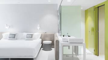 Een moderne hotelkamer met een bed, nachtkastje en een kleine, ronde prullenbak.