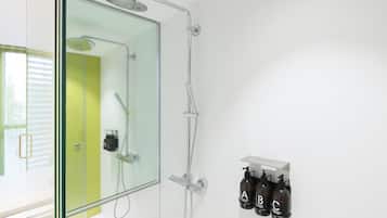 A modern bathroom with a glass shower enclosure, a large mirror, and a wall-mounted soap dispenser.