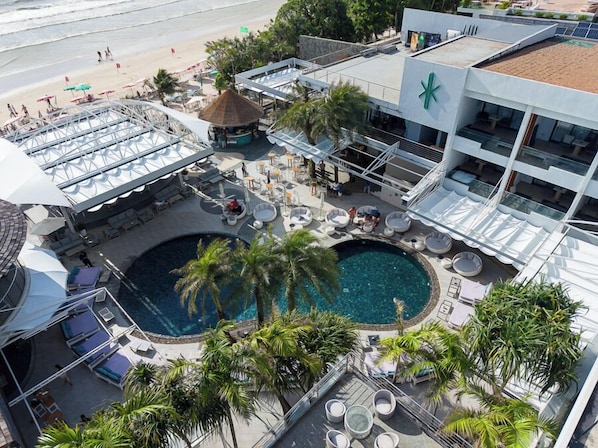 Zona de piscina en la azotea con sillones de descanso y una piscina, rodeada de palmeras y vista a la playa.