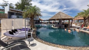 Zona de piscina con sillones, un área de estar techada y un edificio de diseño moderno.