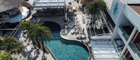 A rooftop pool area with lounge chairs and a central pool, overlooking a beach.