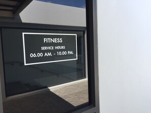 A sign on a window indicating fitness service hours from 06:00 AM to 10:00 PM. - Kudo Hotel & Beach Club (Adults Only) (Patong)
