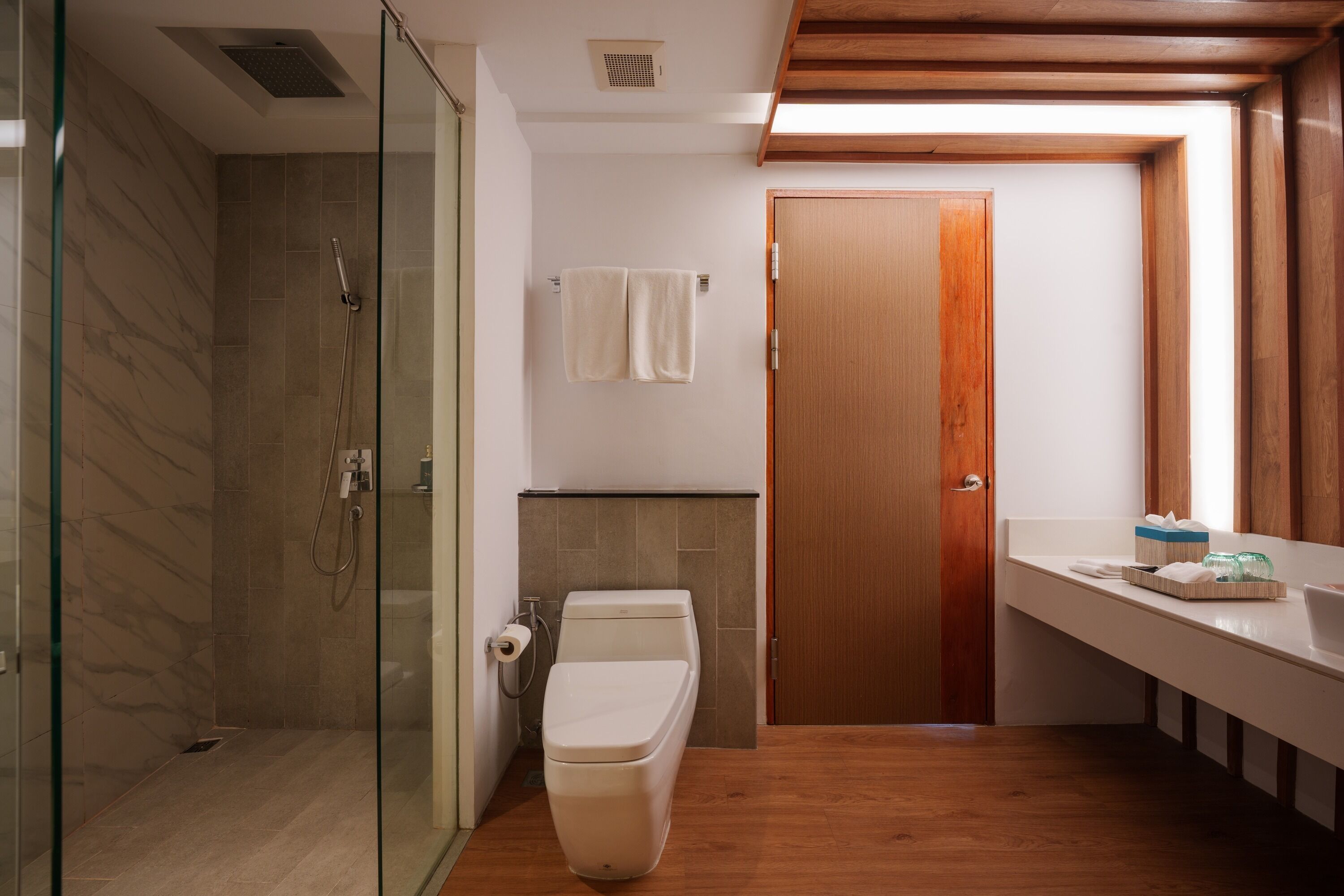 Ein modernes Badezimmer mit Duschkabine aus Glas, Toilette und Holztür.