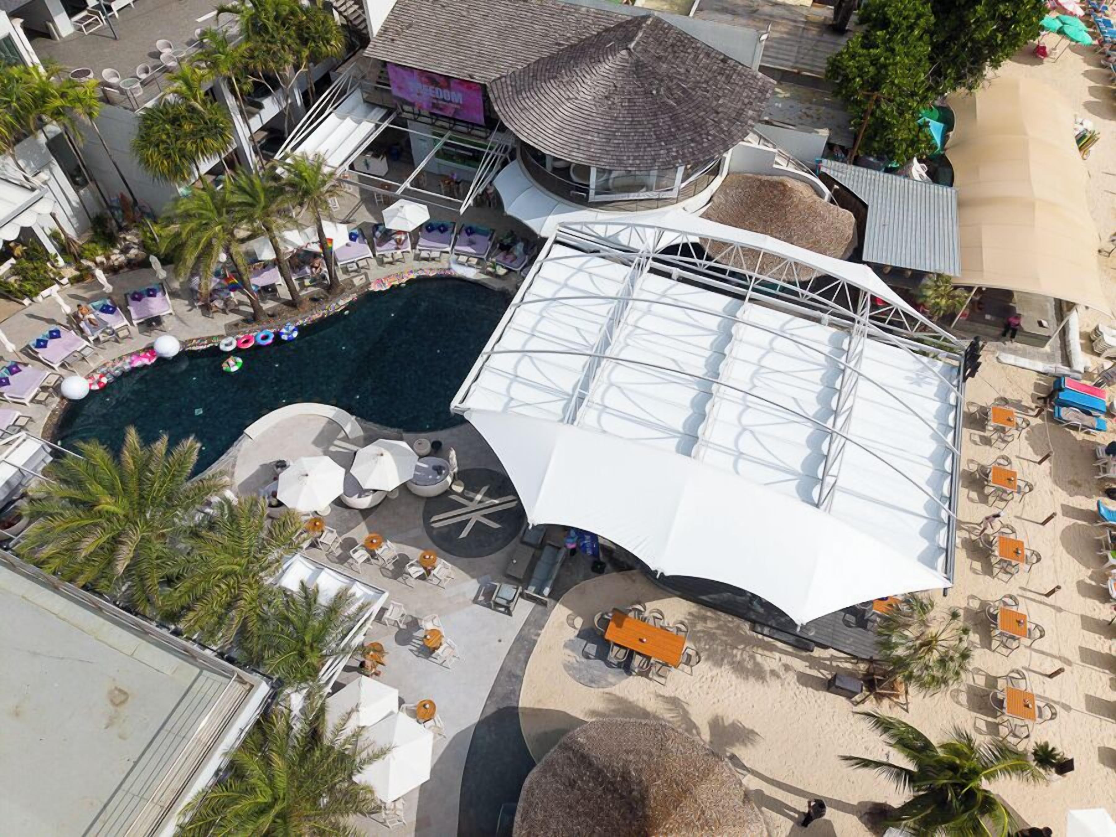 A resort with a swimming pool, lounge area, and beach chairs.