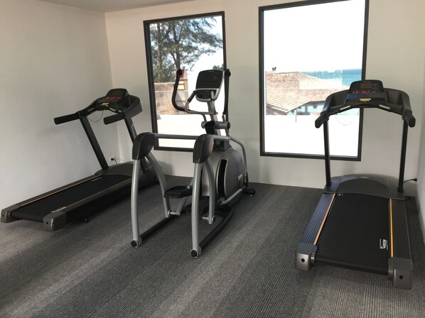 Three exercise machines in a room with large windows. - Kudo Hotel & Beach Club (Adults Only) (Patong)