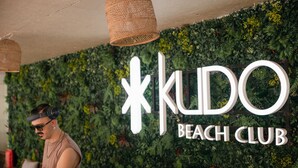 A wall with a sign that reads 'KUDO BEACH CLUB' and a person wearing headphones. - Kudo Hotel & Beach Club (Adults Only) (Patong)