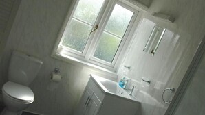 A bathroom with a toilet, sink, and window. - The Admirals Inn Guest House (Bracknell)