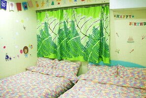 A room with a bed, a green curtain, and a wall with a 'Happy Birthday' banner. - Wai Fuk Guesthouse (Kowloon)