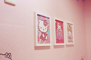 Three framed Hello Kitty artworks on a pink wall.