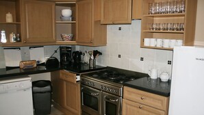 Une cuisine avec des meubles de rangement en bois, une cuisinière, une machine à café et un réfrigérateur.