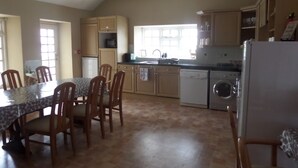 Une cuisine équipée d’une table à manger, de chaises, de placards, d’un lave-linge et d’un réfrigérateur.