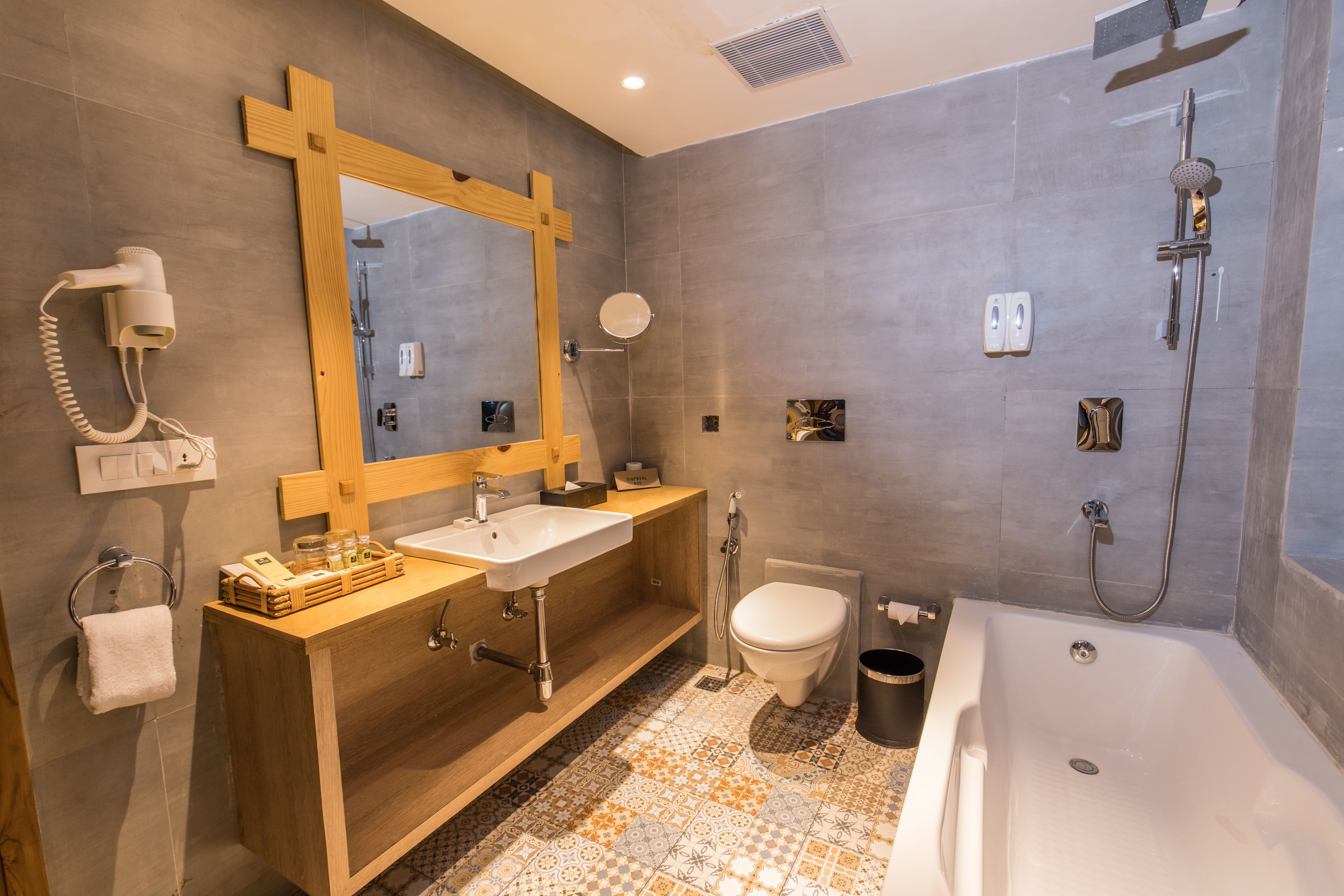 Een moderne badkamer met een houten wastafel, een wastafel, toilet, bad en douche.