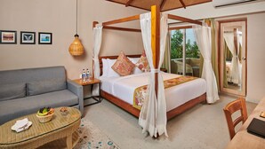 A bedroom with a four-poster bed, a sofa, a small table with a fruit basket, and a view of the outdoors.