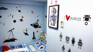 A bedroom with a bed, a wall with space-themed decals, and a framed picture of a robot. - Ridor Guesthouse (Kowloon)