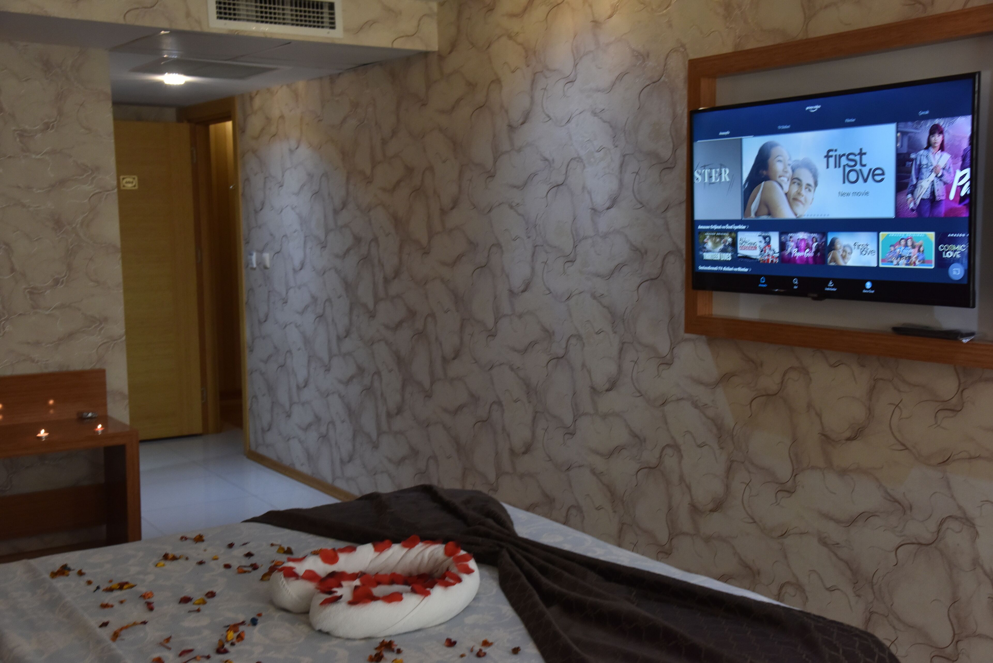 Una habitación de hotel con una cama, un televisor en la pared y un papel tapiz estampado.