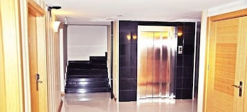 Um corredor com escada e elevador.