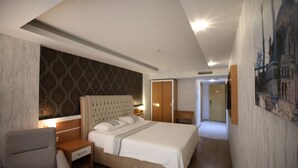 A modern hotel room with a large bed, a nightstand, a chair, and a wardrobe. - Bayazit Hotel (Iskenderun)