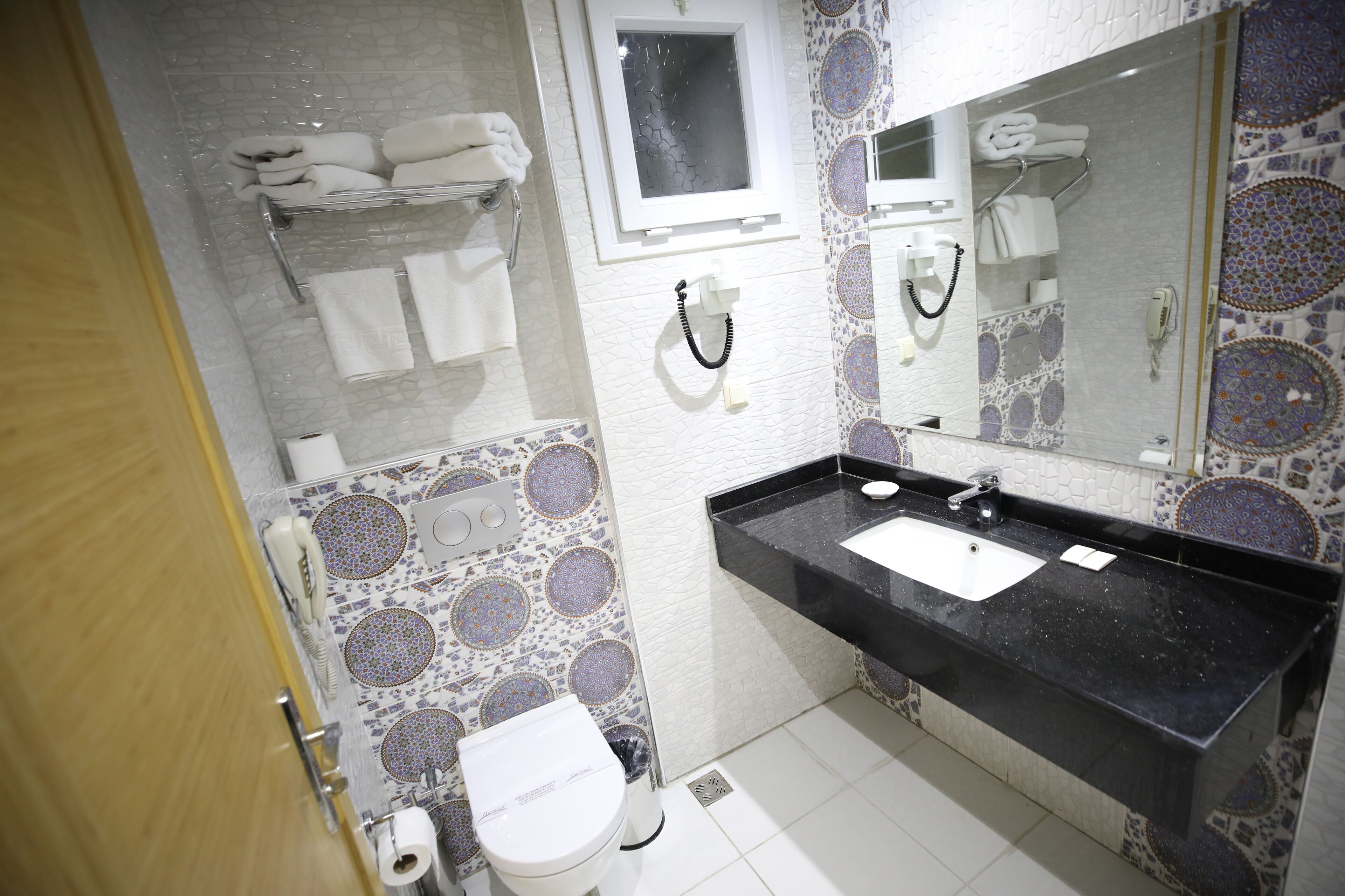 A bathroom with a black sink, white toilet, and patterned tiles.