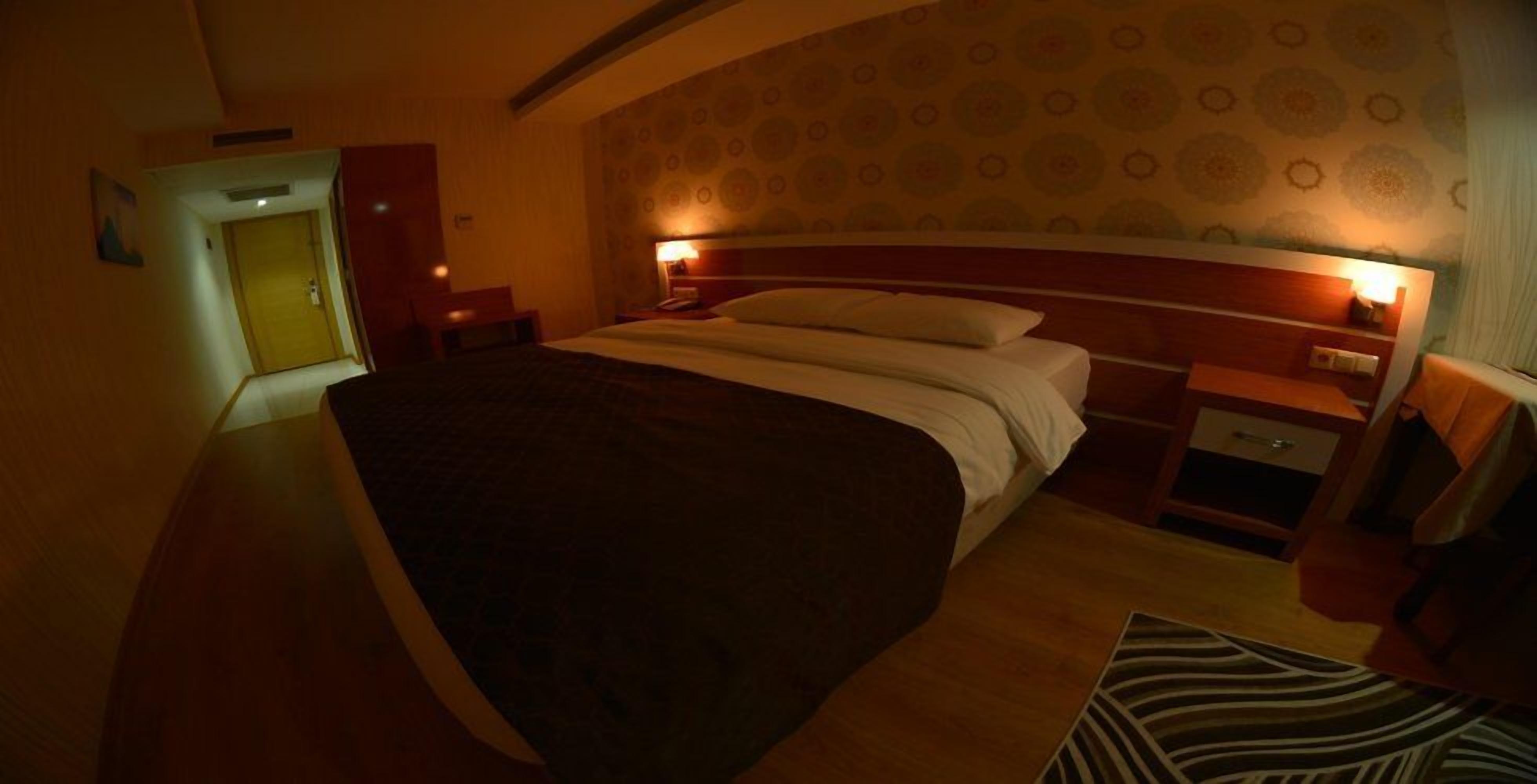 Una habitación de hotel con una cama grande, una mesita de noche y un armario.