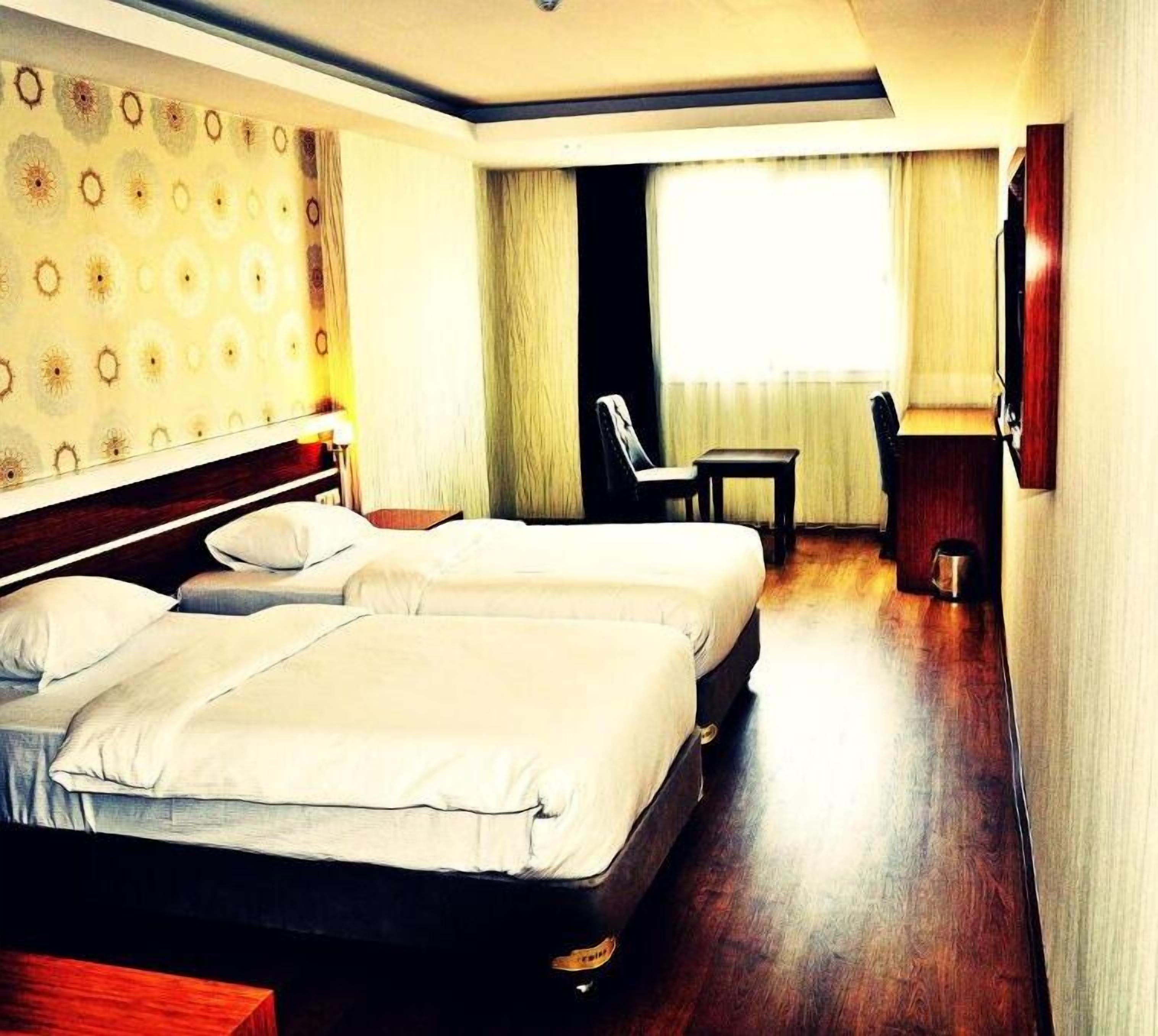 Une chambre d’hôtel avec deux lits, un bureau et une chaise.