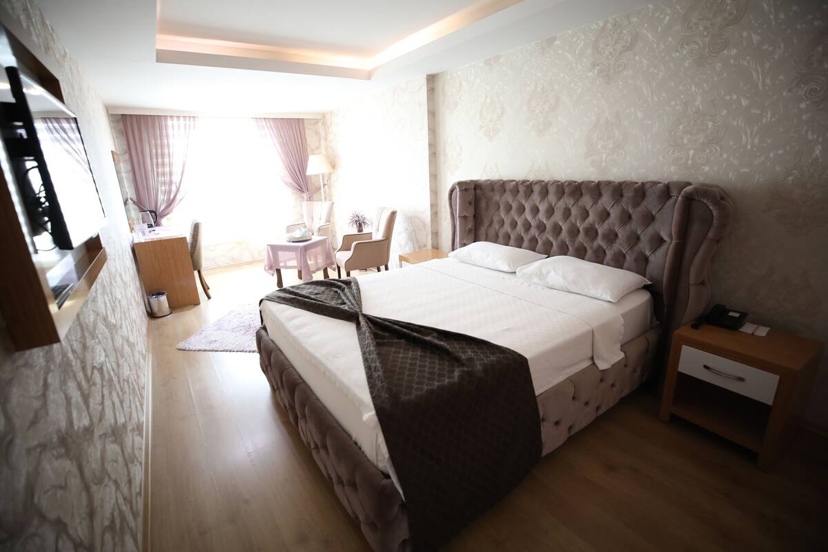 A bedroom with a large bed, a desk, and a chair.