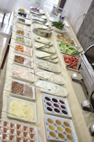 Buffet com diversos alimentos dispostos em bandejas.