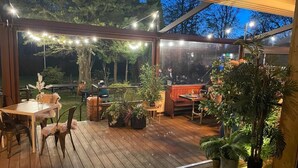 An outdoor deck with wooden flooring, potted plants, and string lights. - The Admiral Cunningham Hotel (Bracknell)