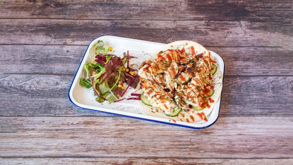 A rectangular plate with a salad and a grilled dish on a wooden surface.
