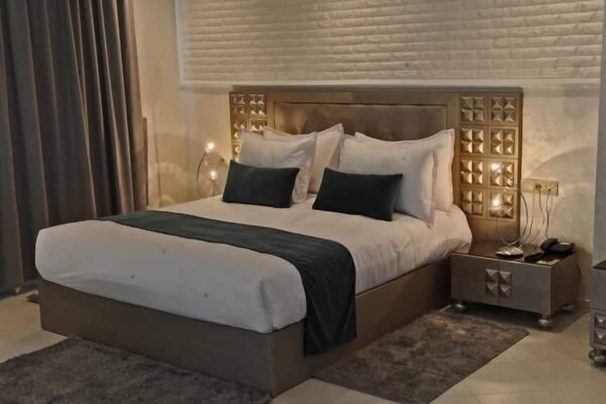 A modern bedroom with a large bed, two bedside tables, and a decorative headboard.
