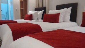 A hotel room with two beds, each with white bedding and red accents.