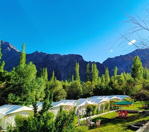 A campsite with tents, a grassy area, and mountains in the background. - Mountain Camp (Leh)