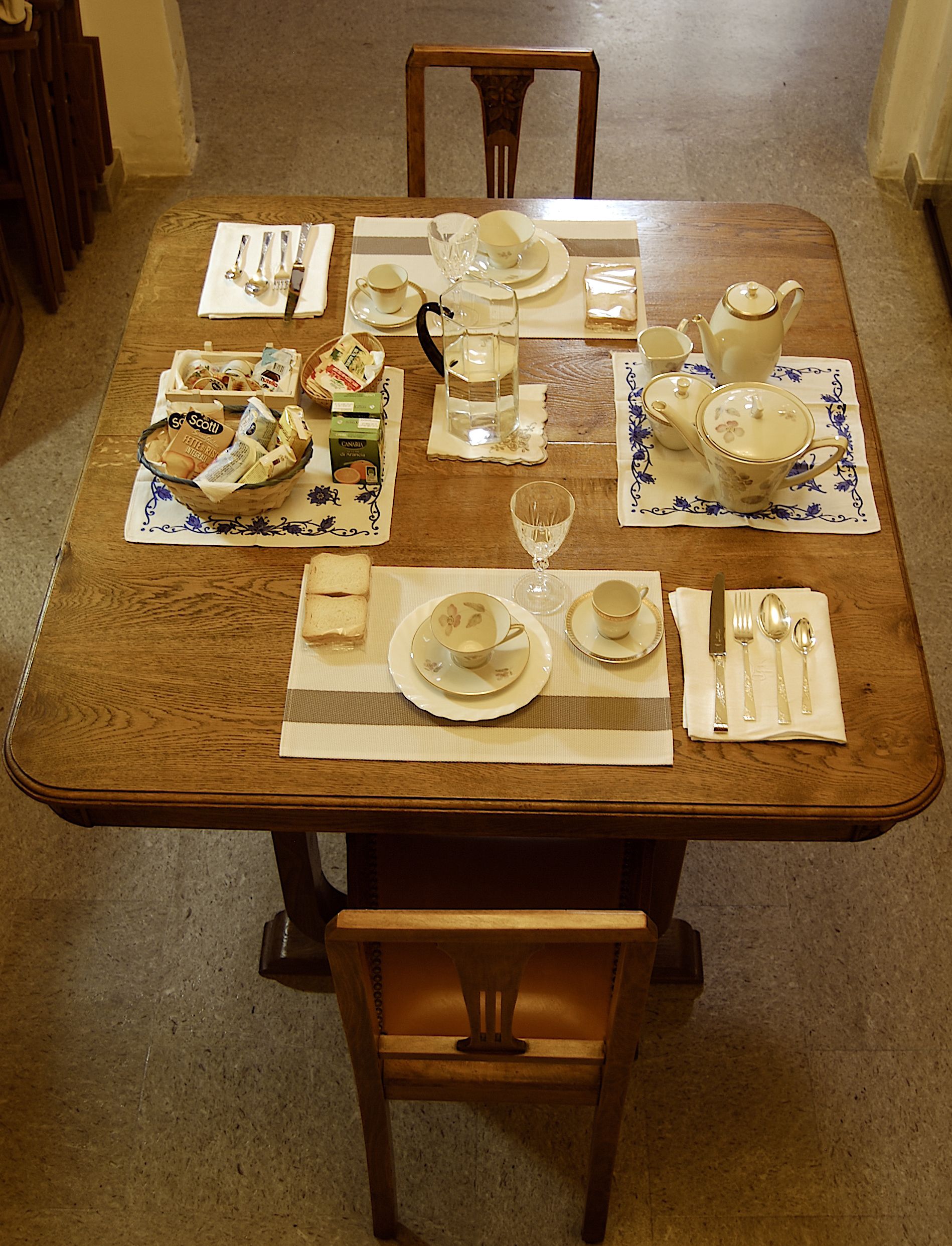 A wooden dining table set with plates, bowls, cups, and cutlery.