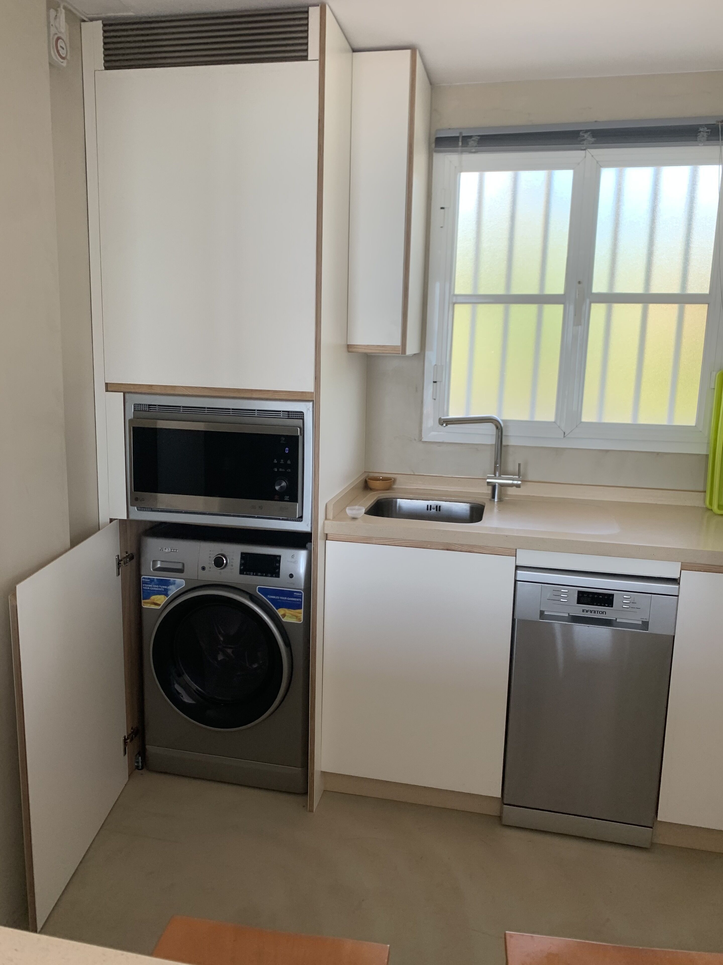 Uma cozinha compacta com máquina de lavar, micro-ondas e máquina de lavar louça.