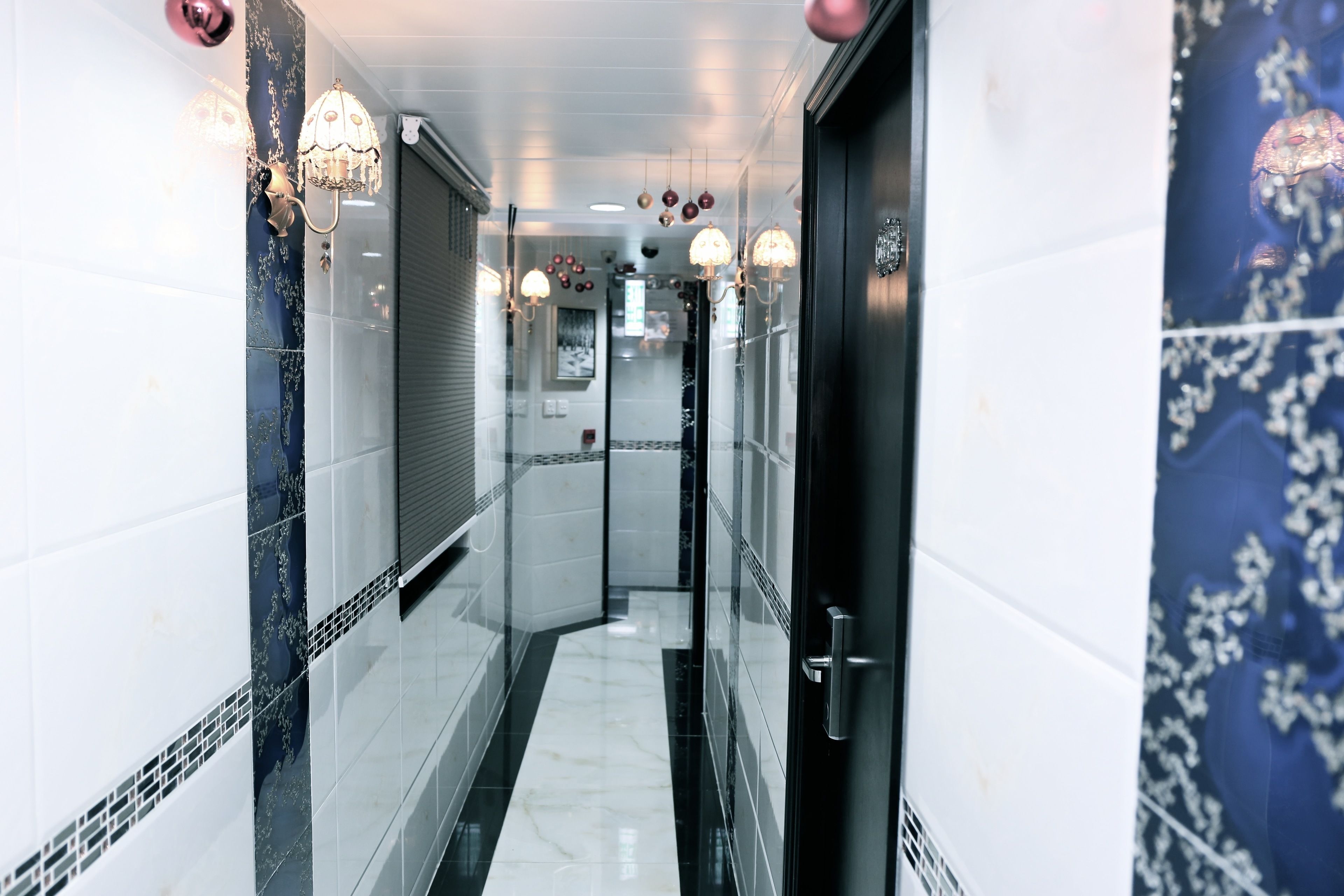 A corridor with tiled walls, a glass door, and hanging lights.