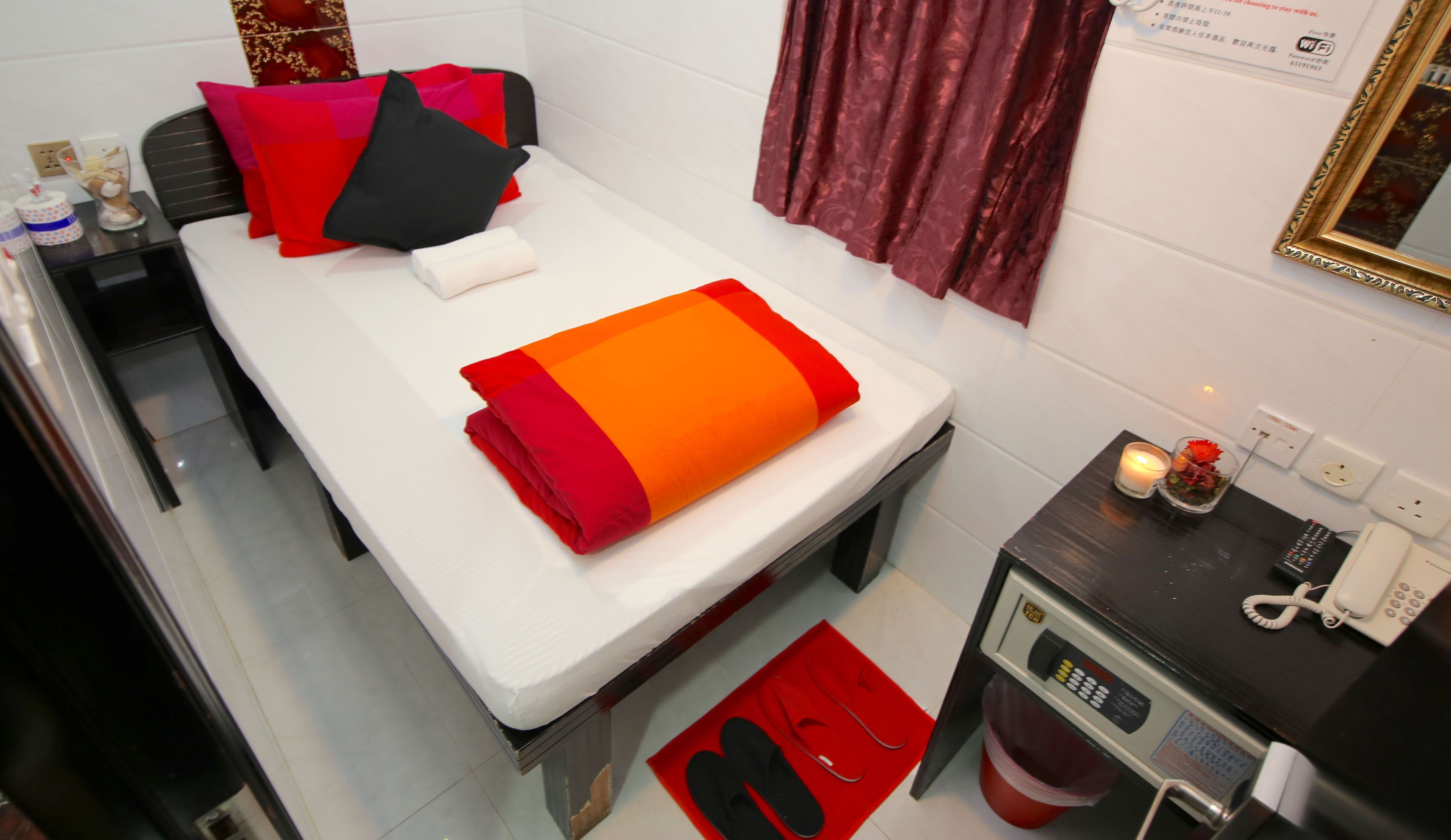 Une chambre d’hôtel équipée d’un lit, d’un bureau, d’un téléphone et d’une poubelle.