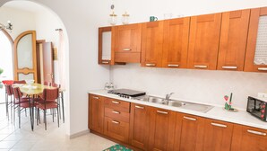 Una cocina con armarios de madera, un fregadero y una zona de comedor con sillas y una mesa.