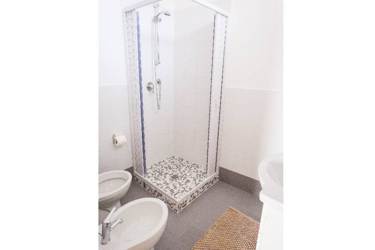 Un baño con cabina de ducha de vidrio, inodoro y lavamanos.
