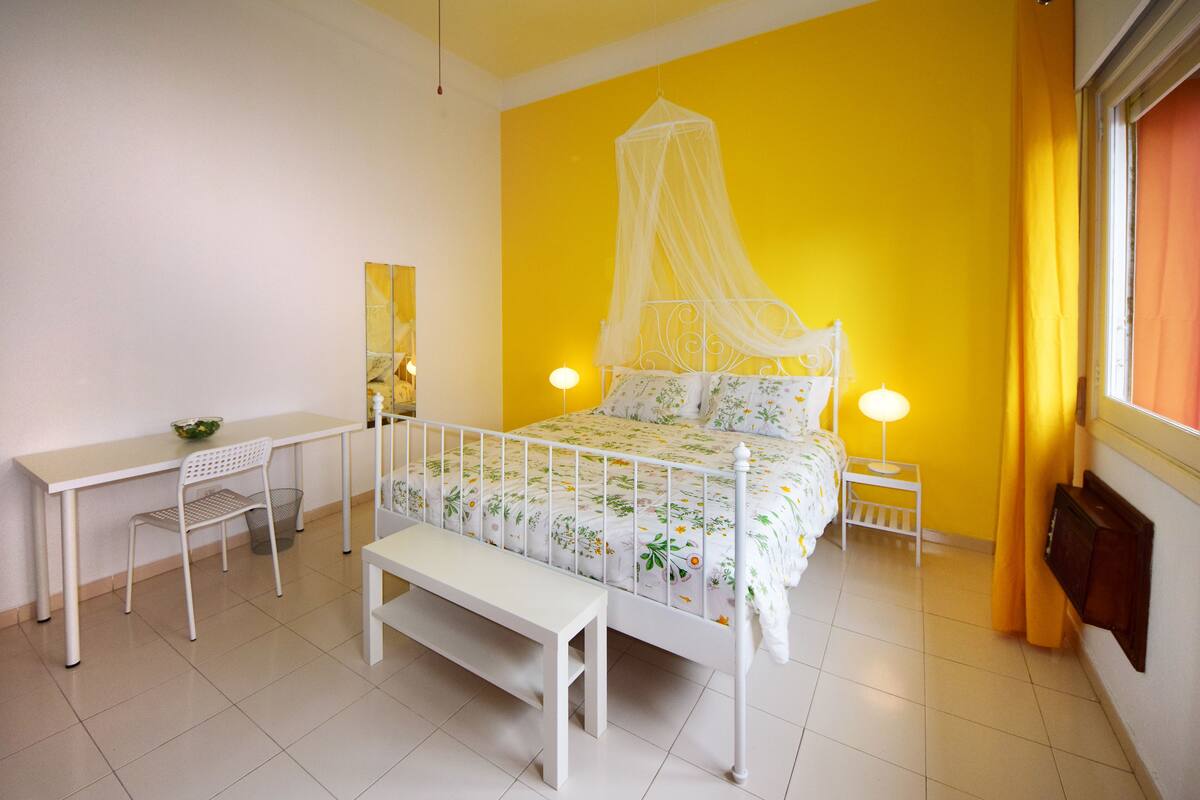 Une chambre à coucher comprenant un lit, des tables de chevet, un banc, un bureau et une chaise.