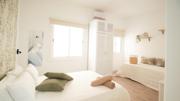 Ein Schlafzimmer mit Bett, Nachttisch, Kleiderschrank und Fenster.