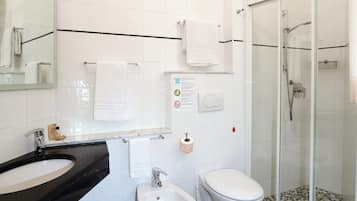 Un bagno moderno con lavandino nero, wc bianco e doccia con pareti in vetro.