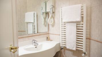 A bathroom with a white sink, a mirror, a towel rack, and a towel warmer.
