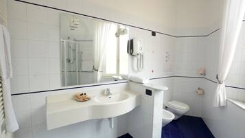 Une salle de bain avec un lavabo blanc, un miroir, des toilettes et un espace douche.